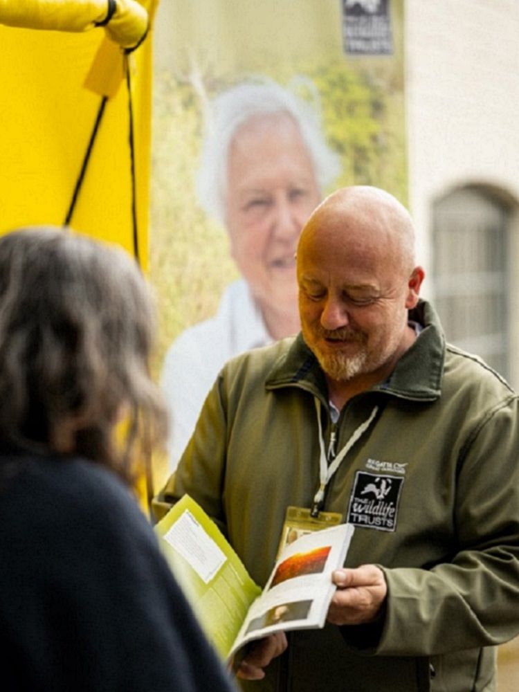 Local Wildlife Trust membership recruiter shows booklet to a member of the public